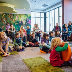 children and adults listening to a story in the children's room at the library