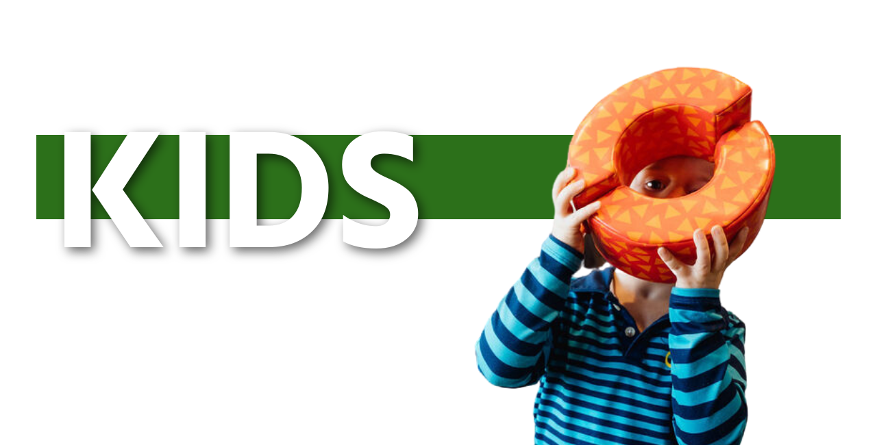 cutout of child holding a circle toy in front of his face and "kids" banner